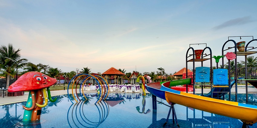An image of a water park in Maharashtra surrounded by palm trees and sunny skies.