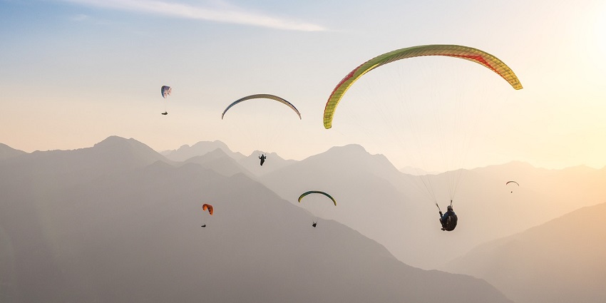 A view of people enjoying a thrilling activity in the clear blue skies during the day.