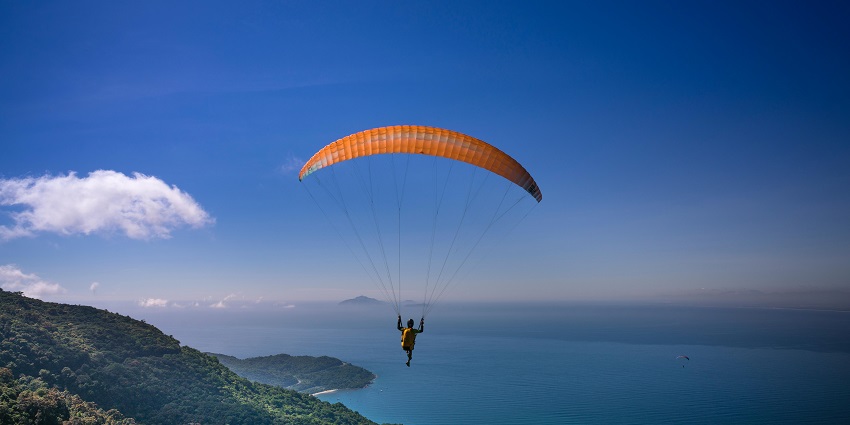 A view of a person gliding high up in the air above the majestic mountains in Karnataka.