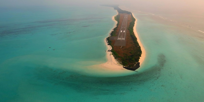An aerial view of the Agatti dotted with palm trees and surrounded by glistening waters.