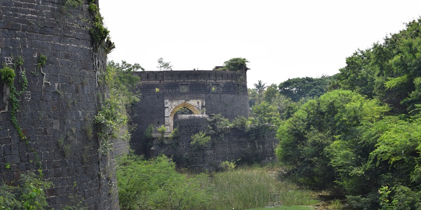 An image showcasing the impressive gates of Ahmednagar Fort against a blue sky
