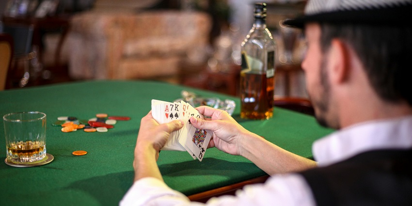 A man holding playing cards, focused on a game with a blurred background.