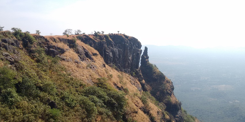 A picture of the ruins of a historical fort on the edge of a cliff in Alibag with a trench visible