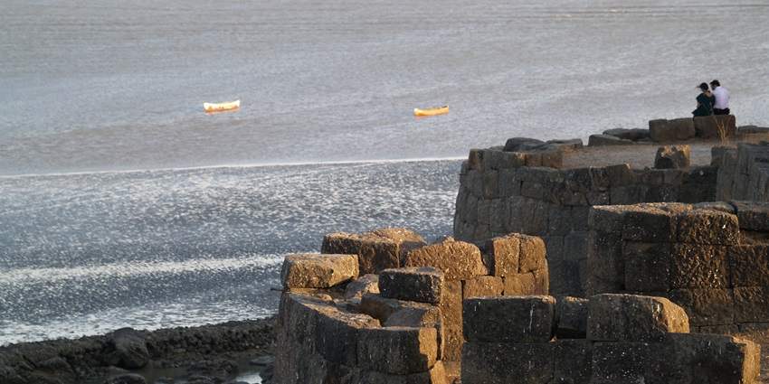 View of Alibag Fort ruins by the sea with rocky shore and cloudy sky–places to visit near pune within 300 km