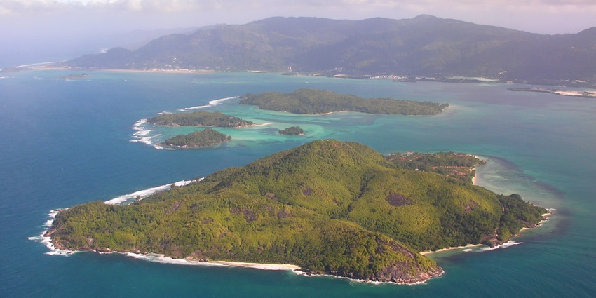 A beautiful view of an island showing rocky shoreline, and dense greenery.