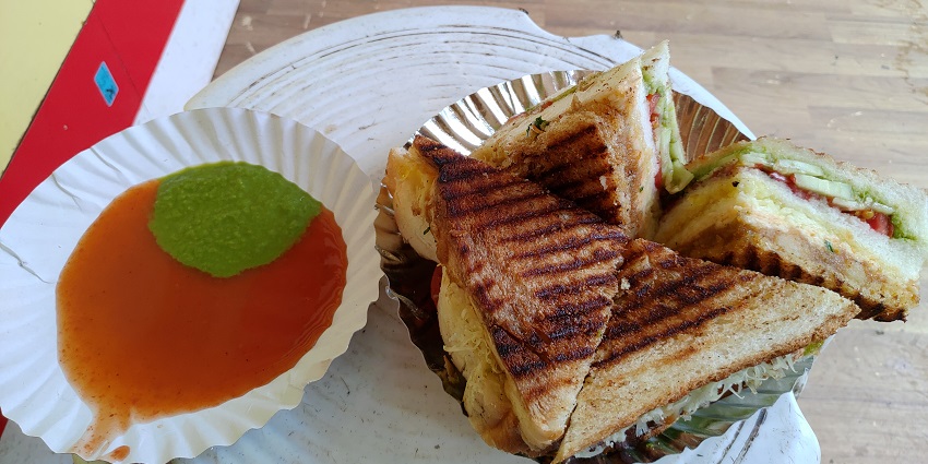 Loaded vegetable cheese grilled sandwich served with ketchup and spicy green chutney.