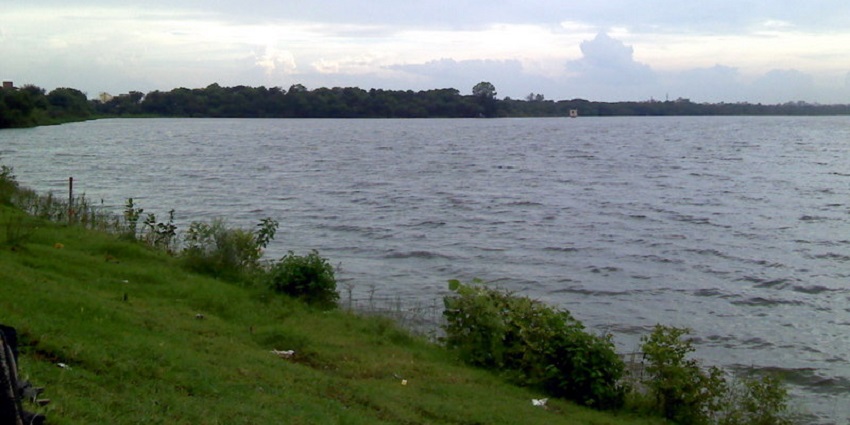 A peaceful view of Ambazari Lake with calm waters surrounded by trees and blue skies.