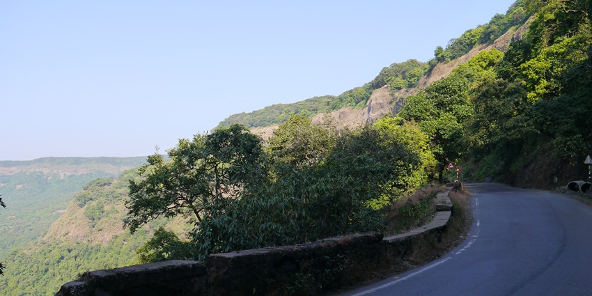 Scenic Amboli Ghat with dense forest greenery and mist-covered hillside road.