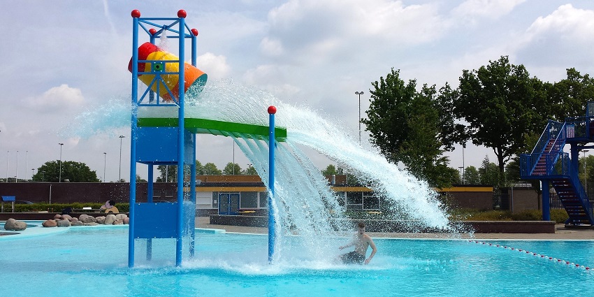 An aerial image shows a swimming pool with clear blue water splashing out for fun.