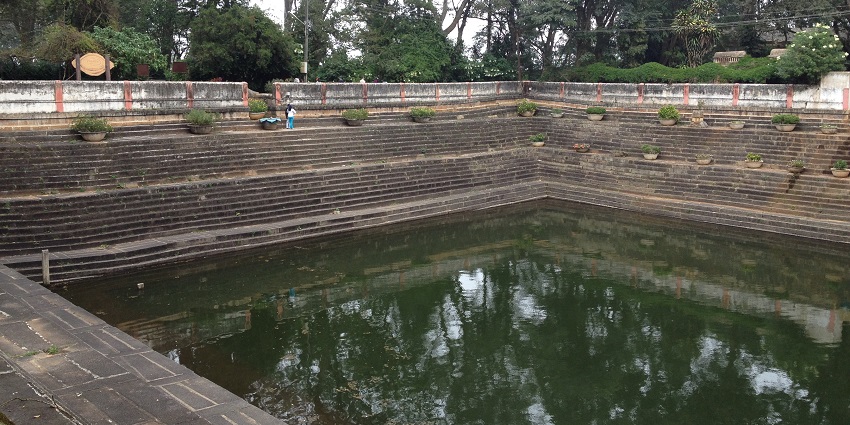 A view of the Amruth Sarovar featuring shimmering blue waters and lush greenery.