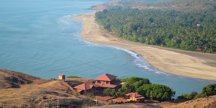 Anjarle Beach in Maharashtra, India, showcasing golden sand, gentle waves, and top hills.