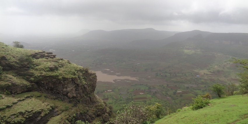 A mist-covered hill at Anjaneri in Nashik, with lush green surroundings and cloudy weather.