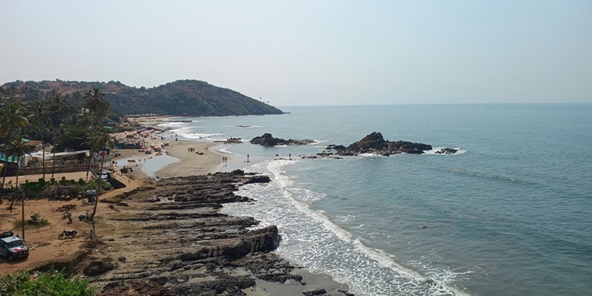 A scenic view of Anjuna Beach with sandy shoreline, one of the best places to visit near Aguada Fort.