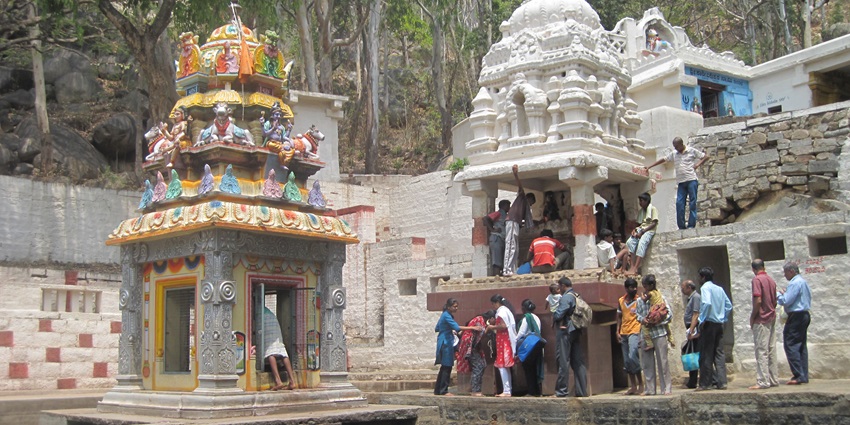 A picture of a temple at a mountain peak with devotees waiting in lines to pray