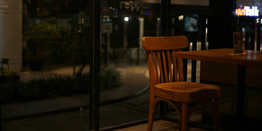 Image of a cafe chair and table from inside with glass background at night view