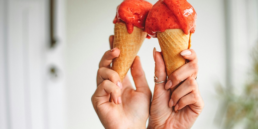 Two Creamy scoops of Ice-cream served in a bowl garnished with a cluster of mint leaves.