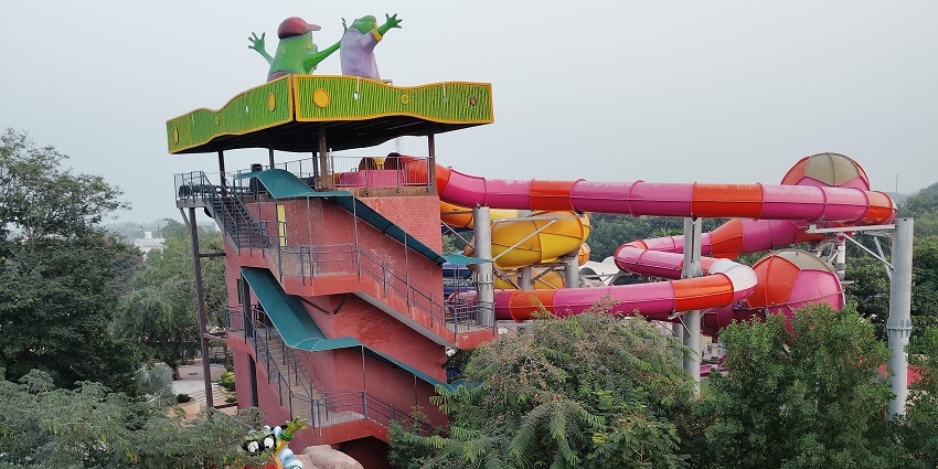 A picture of a water park taken from outside with tall and colourful slides visible