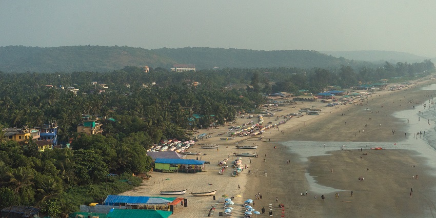 A picture of a beach in Goa taken from a distance with people enjoying the shore