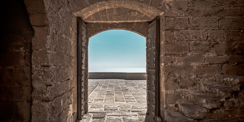 The entrance of Arnala Fort features a stone archway, on a rough and difficult terrain.