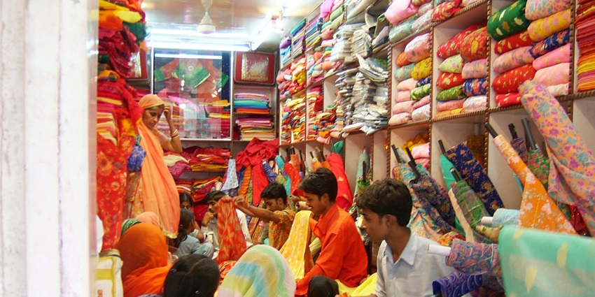 A picture of a local saree store in Dadar with the shopkeeper showing sarees to the customers