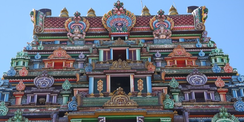 A picture of the colourful Gopuram of a Murugan temple with intricate carvings