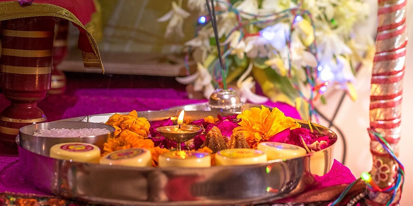 A puja thali, adorned with several items like diya, prasad, and flowers during a puja.