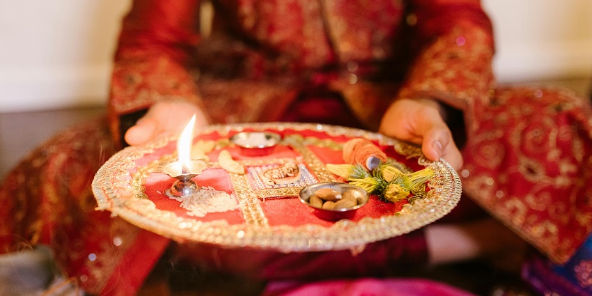 A picture of a plate decorated with flowers and diyas, used to seek blessings from god