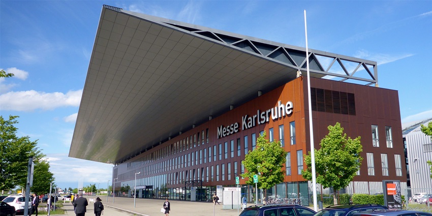 Main entrance of Messe Karlsruhe with overhanging roof and glass façade.