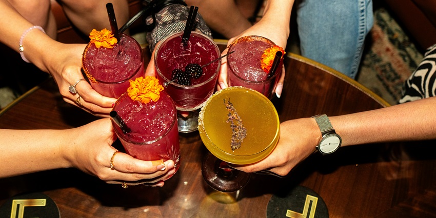 A group of ladies partying and doing cheers with their colourful fruit drinks