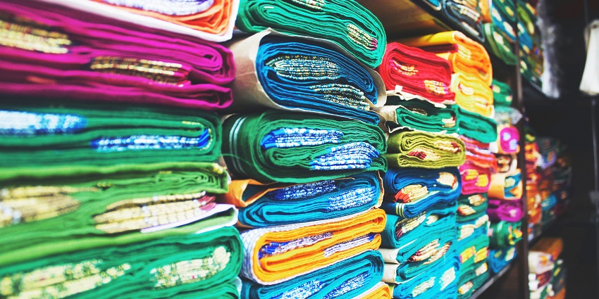 Vibrant saris and beach accessories on sale at a beach road market for shopping in Alibaug.