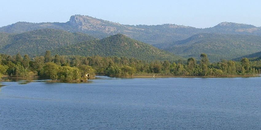 A picture of a mountain range near Bangalore visible behind a serene lake