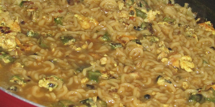 Soupy Maggie in a cauldron topped with shredded eggs, green chilli, onion and spices