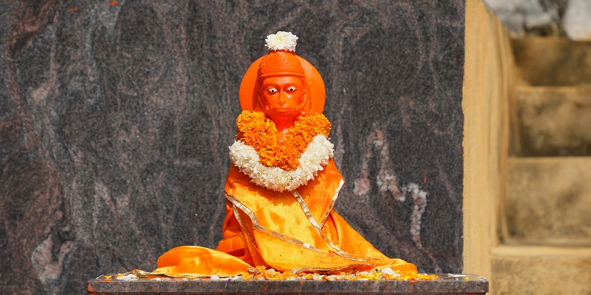 A small statue of Lord Hanuman at Anjaneya Hill on a pedestal with a stairway going up