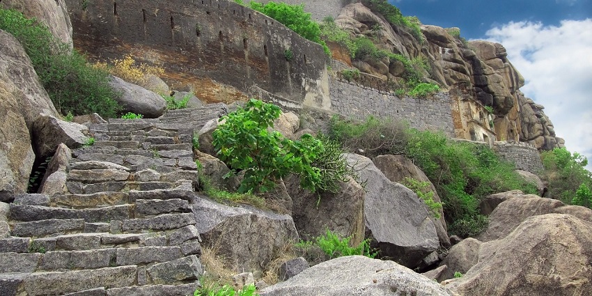 Stone ruins of an ancient structure sit on a mountain, a popular destination near Akola Fort