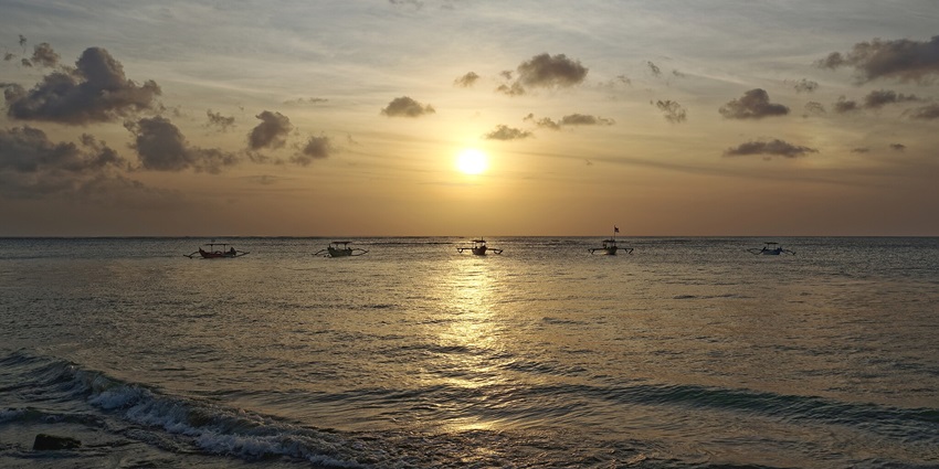 Serene sunset on the beach in Kuta with cosy kayaks on the horizon in Bali, Indonesia