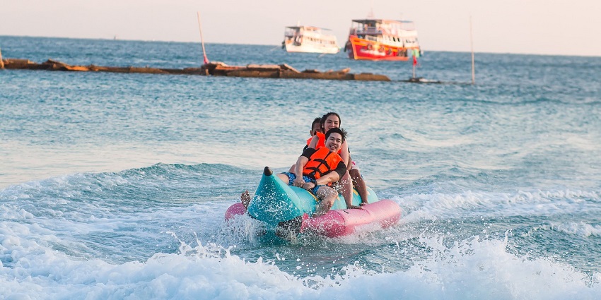 People enjoying a banana boat ride at Mulshi Dam, laughing and holding on tight.