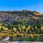 A scenic vista of a majestic mountain dotted with lush green vegetation in Karnataka.