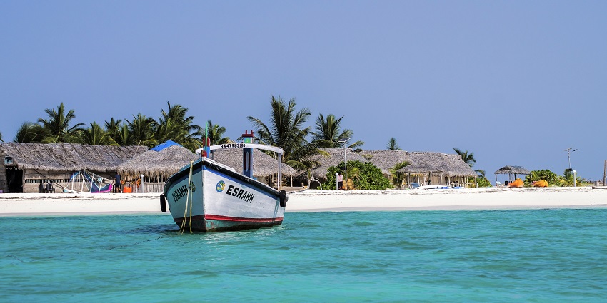 Image of Bangaram beach with a boat near the shore and resting area during day time