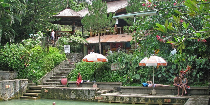 An image of the Banjar Hot Springs with stone-carved fountains flowing warm water into pools