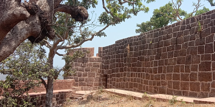 Scenic view of Bankot Fort against a clear blue sky and lush greenery