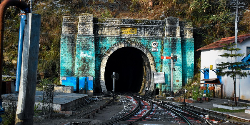 An image of a train travelling through a tunnel next to a forest at Barog, Himachal Pradesh.