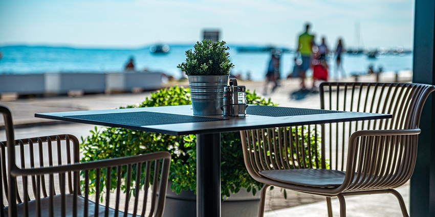 An image showing a cosy beachside café, offering a picturesque view of the ocean under a bright, sunny sky.
