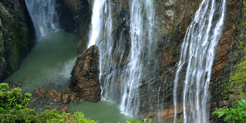 Beema Falls cascading through dense forest trail in Javadu Hills, surrounded by sandalwood trees.