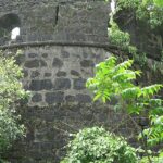 A distant view of the ruins of Belapur Fort, located in Navi Mumbai, surrounded by greenery.