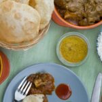 An image of dishes cooked in Maharashtrian style from Pune, like rice, dal, egg gravy, puri, etc.