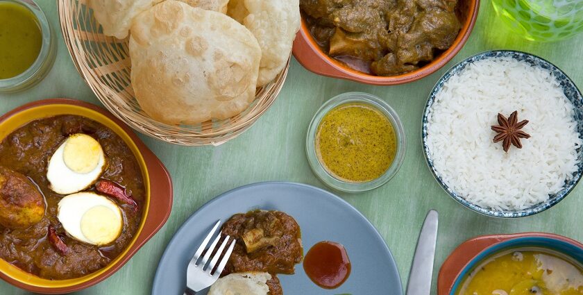 An image of dishes cooked in Maharashtrian style from Pune, like rice, dal, egg gravy, puri, etc.