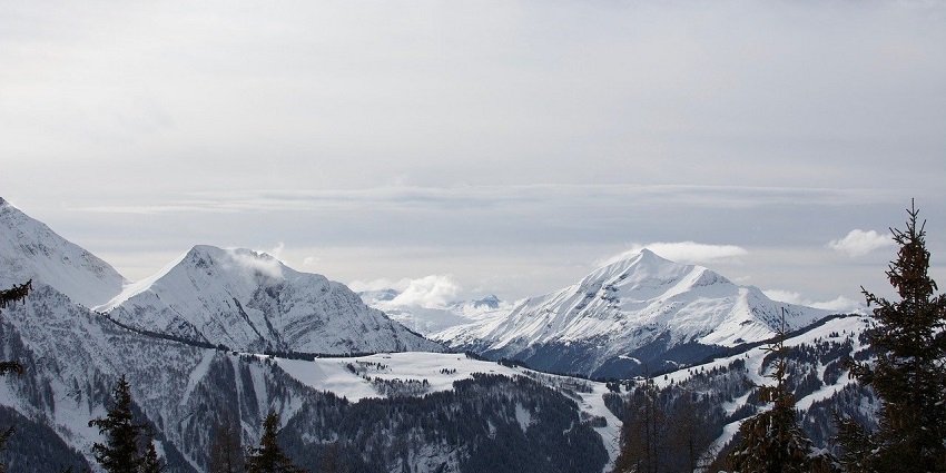 Snow-capped mountain peaks rise majestically against a clear blue sky, showcasing beauty.