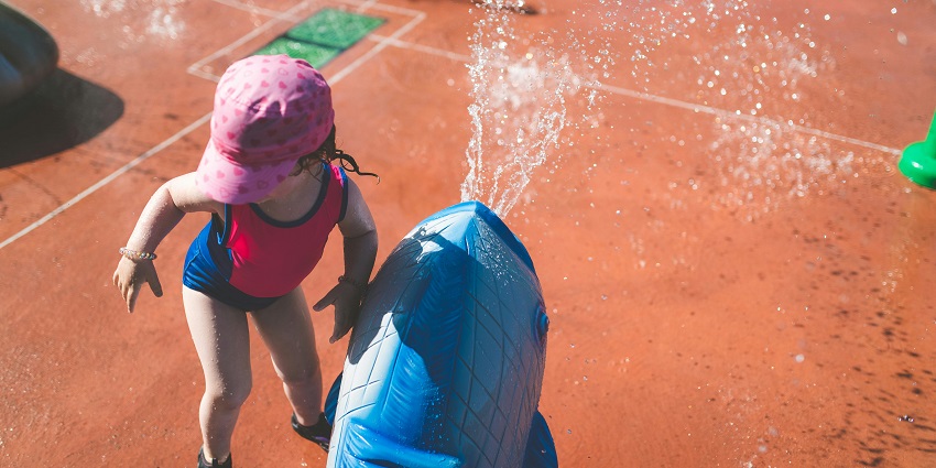 Little girl playing in a water park, splashing in the water and enjoying the fun attractions.