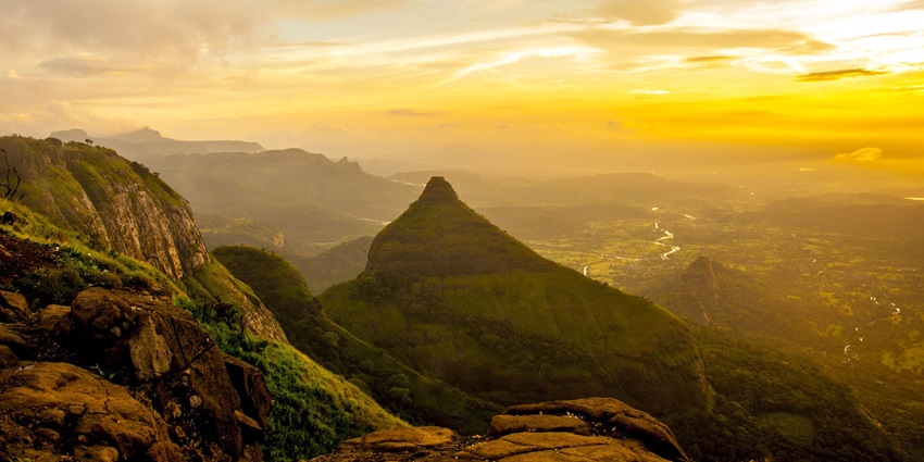 Misty clouds cover the green hills during monsoon, creating a dramatic landscape.