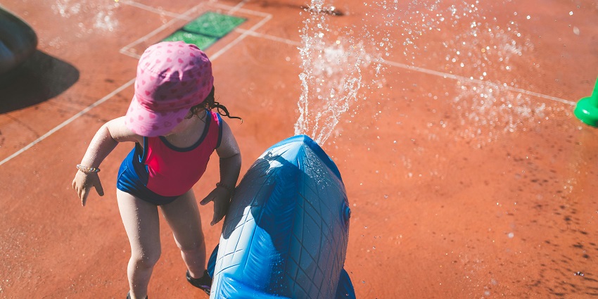 Little girl joyfully playing in a water park, splashing in the water, and enjoying the fun attractions.